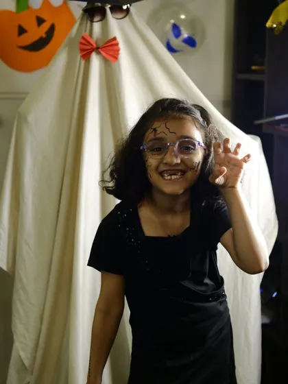 A student showing off her spooky makeup in front of our ghost decoration during the Halloween party.