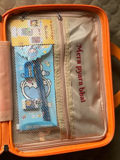 The inside lid of the suitcase hamper, which has a mesh pocket perfect for holding smaller items like this stationery pouch. I also added a "Mera pyara bhai" sticker.