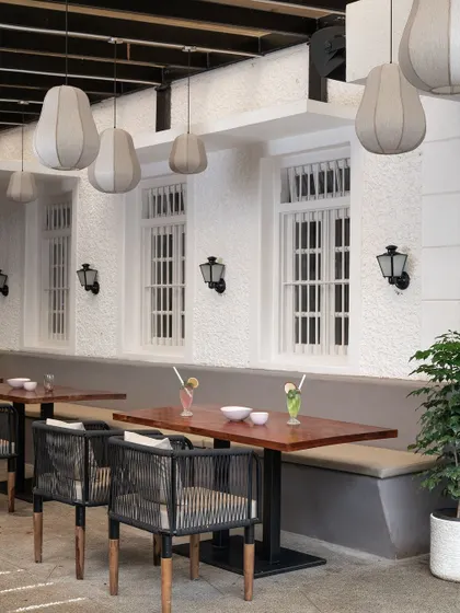 What was once a simple veranda is now a chic outdoor seating area. I kept the original white textured walls and windows, pairing them with modern woven chairs and fabric pendant lights to create a breezy, tropical feel.