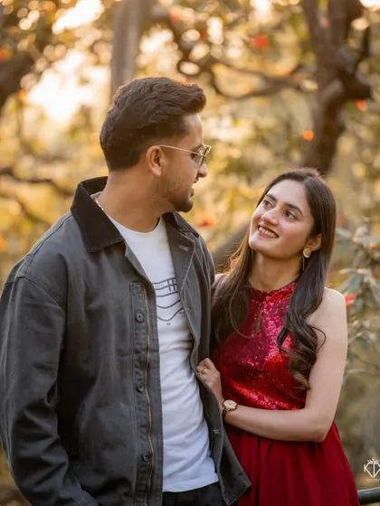 A sweet, candid interaction between the couple, with the warm, golden light filtering through the trees in the background.
