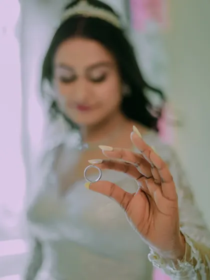 A close up, artistic shot of the bride holding her wedding ring, a symbol of her lifelong commitment.
