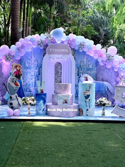 This outdoor Frozen theme for Vydoorya's fifth birthday was a spectacular winter scene. The full setup included a grand balloon arch over a castle backdrop, character cutouts, and a large marquee number '5'.
