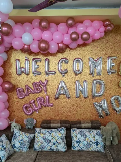 A cozy 'Welcome Baby and Mom' setup in pink and rose gold against a textured gold wall, perfect for celebrating their return home.