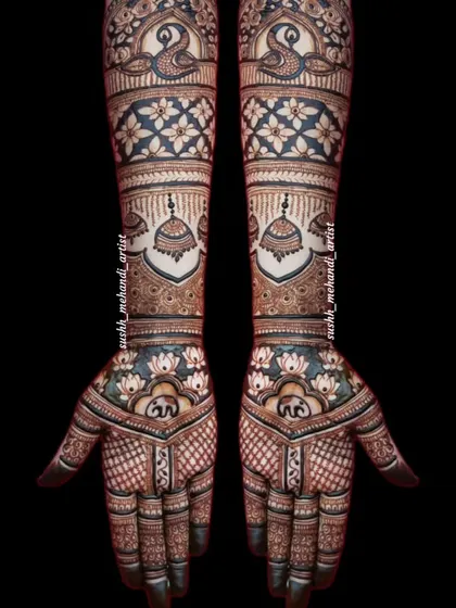 This full bridal design is rich with detail, featuring peacocks, jhumkas, and lotus flowers. The dark, bold lines make the pattern stand out.