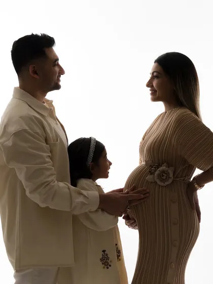 A classic silhouette portrait of the growing family. The soft light and their connected poses create a timeless and artistic maternity photograph.