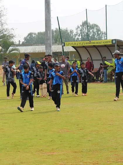 A youth team walks off the field after their match, with the scoreboard visible in the background.