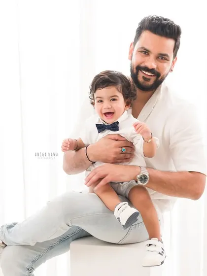 A proud father holds his laughing son. This light and airy portrait is a beautiful testament to the father-son bond.