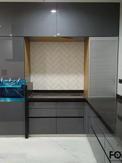 This image shows a dedicated appliance nook with a herringbone tile backsplash, set within dark grey cabinetry. A roller shutter conceals the space when not in use, maintaining the kitchen's sleek appearance.