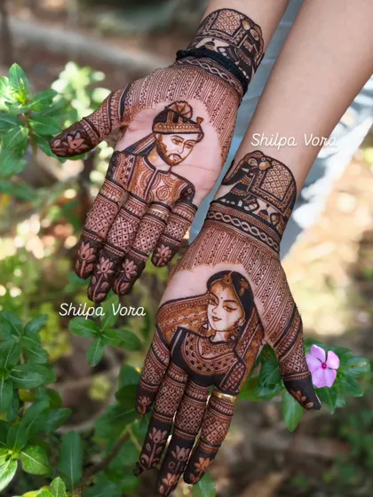 A clear, outdoor shot of my portrait work. The bride and groom figures are the centerpiece, complemented by lotus details on the fingers and traditional patterns on the wrist.