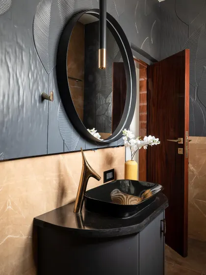 This powder room is an example of how I create "statement" bathrooms. The design uses a bold combination of black textured wall panels, caramel brown marble, and custom sanitary fixtures with gold accents to evoke a sense of dark, understated luxury.