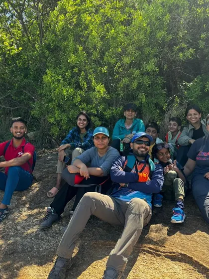 A group of friends and family resting in the shade of a tree during their trek.