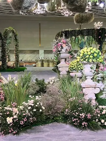 A wide view of the floral landscape created for the event, with garden beds, urns, and trees transforming the space into a veritable Italian paradise.