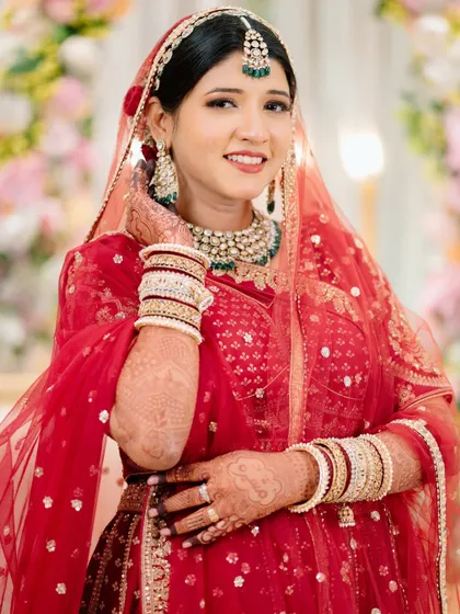 A close-up bridal portrait capturing the bride's beautiful smile and the details of her makeup, jewelry, and henna.