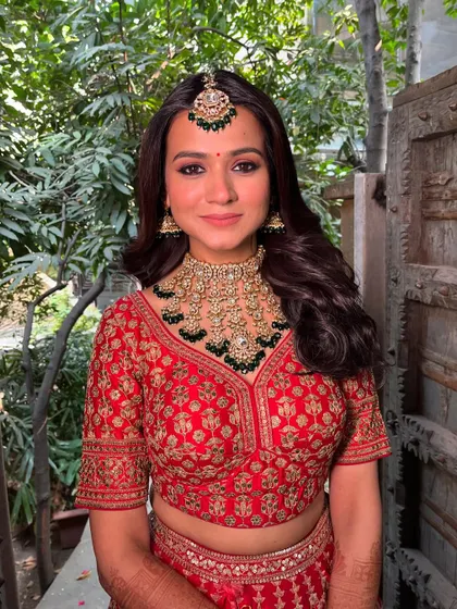 A happy and confident bride, ready for her big day. The makeup is fresh and glowing, with a focus on her signature kohl-rimmed eyes.