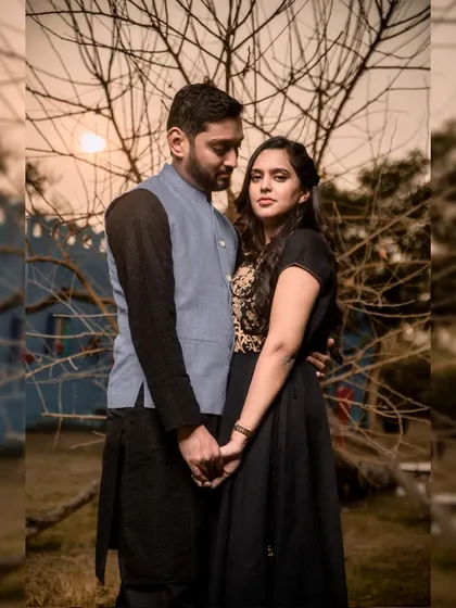 A classic pre-wedding portrait against a dramatic tree silhouette. Their connected hands and serious expressions give this photo a powerful, moody feel.
