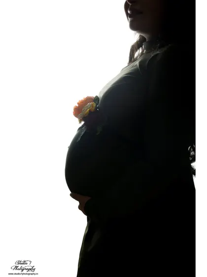 An artistic silhouette shot where the baby bump is adorned with a small flower. It's a creative and subtle way to add a touch of color and symbolism.