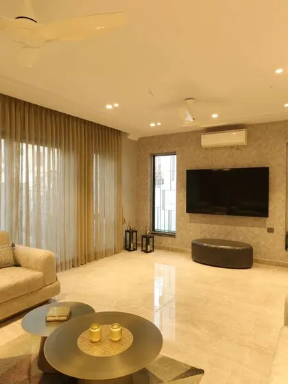 This view highlights the sheer curtains that allow natural light to flood the drawing room, enhancing the airy and inviting feel of the space.