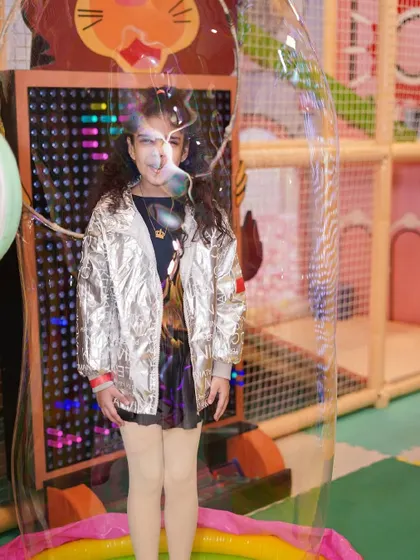 A girl stands inside a giant bubble, a magical and fun activity we offer at our parties.