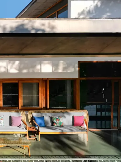 An outdoor seating area sheltered by a large cantilevered concrete roof. This space demonstrates how modern architectural forms can create comfortable, traditional outdoor living zones like verandas.