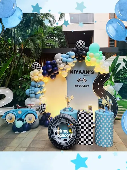 Kiyaan's "Two Fast" second birthday was a stylish affair. The decor featured a modern race car theme with a checkered tire prop, a road floor decal, and a cool blue and navy balloon arch.