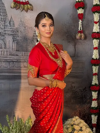 A timeless South Indian bridal look in a classic red Kanchivaram saree. The drape is complemented by heavy temple jewellery for an authentic and regal feel.