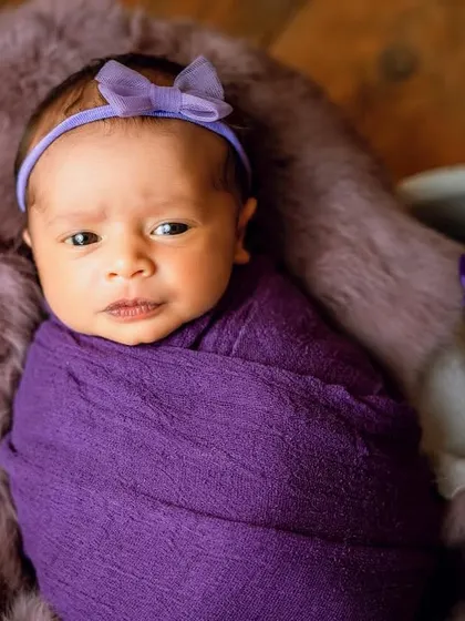 A beautiful newborn wrapped in a rich purple swaddle. I love working with color to create striking and artistic baby portraits.