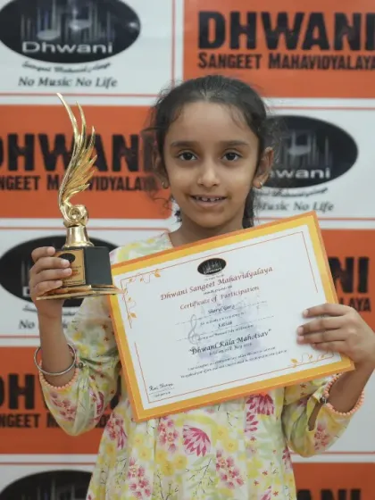 A young student proudly displays her certificate and trophy.