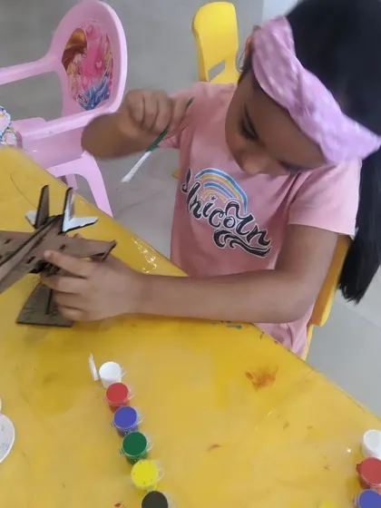 A young girl carefully applies paint to her fighter jet model. We love seeing the unique color combinations each child comes up with.