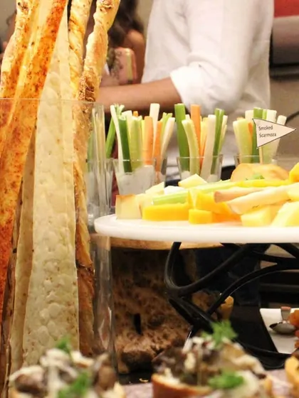 A close-up of the details on our grazing table. You can see the tall, crispy grissini breadsticks, a platter of assorted cheeses, and fresh vegetable sticks ready for dipping.