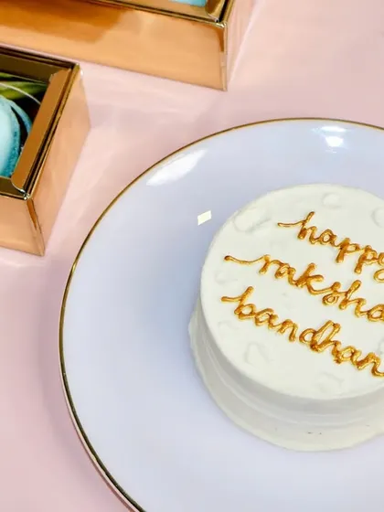A simple and elegant "Happy Raksha Bandhan" bento cake. The gold lettering on a clean white background makes this a classic and heartfelt choice for the festival.