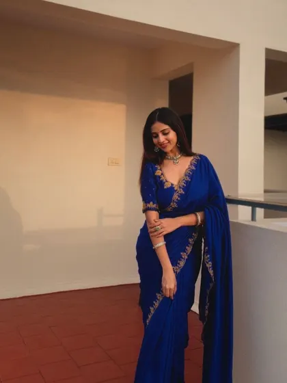 A client looking chic in a royal blue saree with delicate gold embroidery, perfect for an evening event.