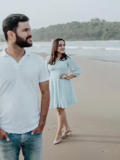 A creative pose with the groom in the foreground and the bride in the background, adding depth and interest to this beach portrait.