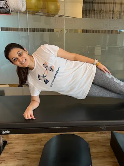 A member performs a side plank on the Cadillac, demonstrating the stability and core engagement required for this advanced move.