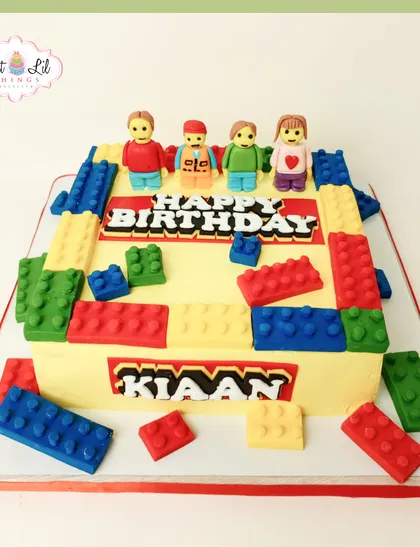 A classic LEGO-themed cake designed for Kiaan's birthday. This rectangular cake is covered in colorful, edible fondant blocks and topped with custom LEGO-style family figures, making it a personal and fun celebration centerpiece.