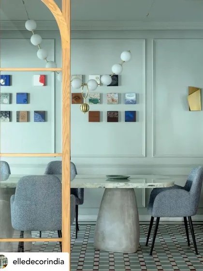 The dining room of Summer Haus, featured in Elle Decor. The space combines a sculptural concrete table with elegant chairs and a gallery wall of small artworks, creating a unique and personal atmosphere.