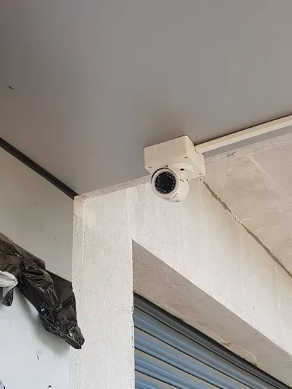 A CP Plus camera installed on a concrete pillar, a common placement for monitoring commercial building exteriors.