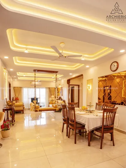 An expansive view of the living and dining area, unified by a sophisticated false ceiling with cove lighting. The layout is open and airy, with the traditional swing acting as a central, inviting feature.