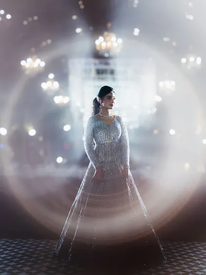A creative portrait of the bride at her sangeet, surrounded by a halo of light from the chandeliers. I use in-camera effects like this to create unique and artistic bridal portraits.