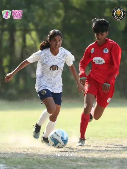 Our player dribbles forward with determination, keeping the ball close while being challenged by an opponent in red.