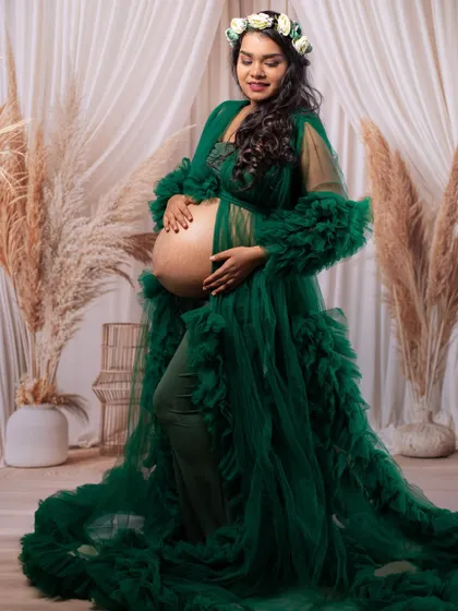 A radiant solo portrait of the mom-to-be in a flowing green gown and floral crown, embodying the beauty of nature and life.