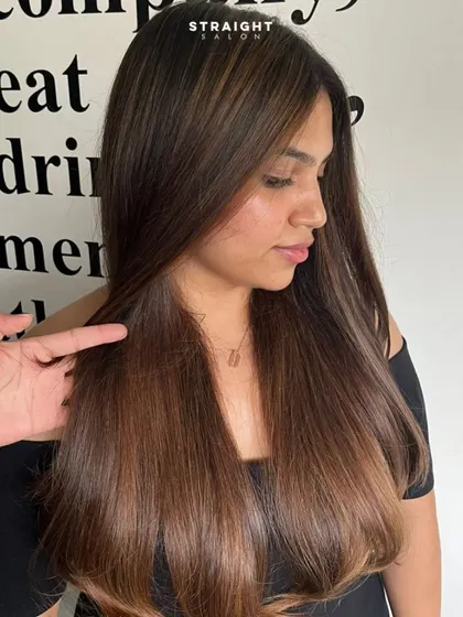 A stylist points to the seamless blend in this straight balayage, showcasing the technique.