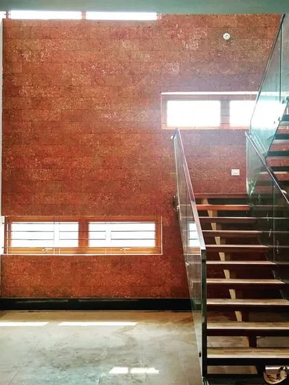 Natural light floods this double-height courtyard, highlighting the texture of the laterite brick accent wall. We designed this space with a modern floating staircase and large skylights to create a vibrant, sunlit core within the home.