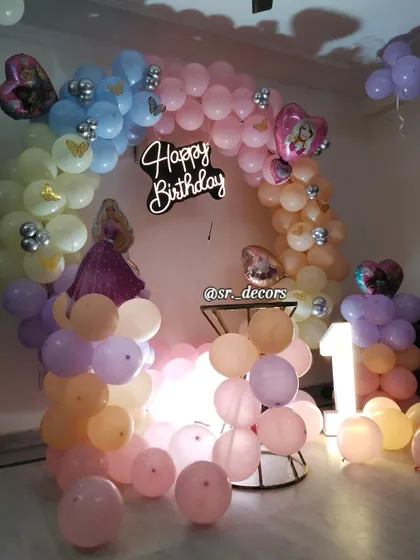 A dreamy 'Barbie' theme for a first birthday, using a pastel rainbow balloon arch and Barbie-themed foil balloons to create a magical setting.
