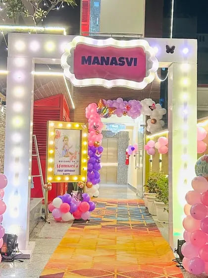 A grand entrance arch for a butterfly-themed first birthday party. The lighted archway, personalized welcome sign, and pink balloon columns create an exciting welcome for guests.