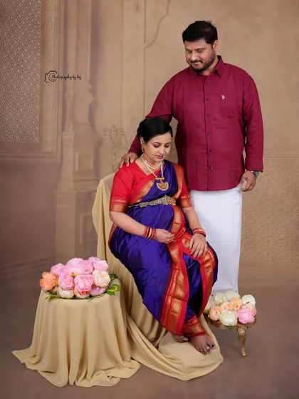 A regal studio portrait of a couple in traditional Maharashtrian attire, seated gracefully with floral props.