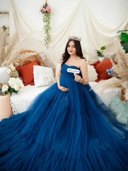 A royal blue dream. This mom-to-be looks stunning in a voluminous blue gown, seated in a boho-chic setting with a tiara.
