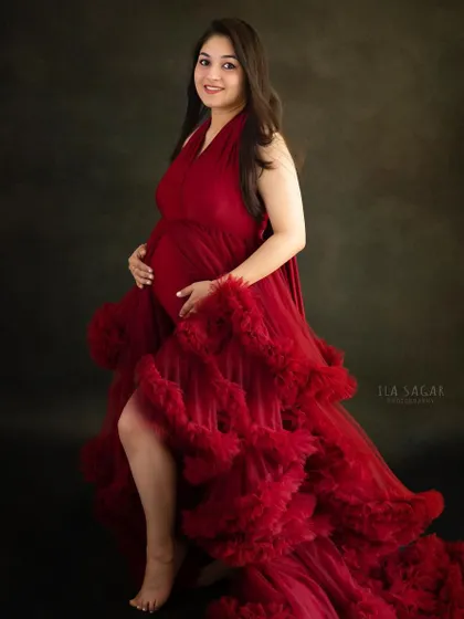 This portrait showcases the beautiful silhouette of pregnancy. The ruffled red gown adds texture and drama, making for a truly memorable maternity photo.