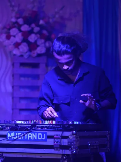 A blue-lit photo of me at the decks, focused on adjusting the levels.