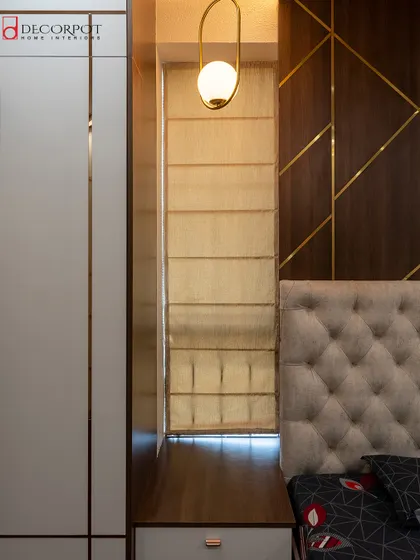 This bedroom features a tufted headboard and a dark wood accent wall with geometric brass inlays. The pendant lights on either side of the bed add a touch of modern elegance.