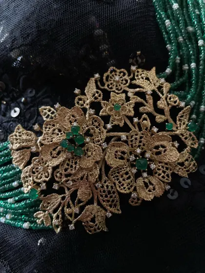 A delicate, lace like gold choker handcrafted in 18k gold. The piece is enhanced with natural diamonds and ethically sourced sugarloaf emeralds, and strung with emerald beads and freshwater pearls.